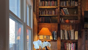 A cozy reading nook with a wooden bookshelf, a table with a chair, and a window with a view of the outside. - Spacious 5-bedroom Lodge nestled at the Gateway to the Sequoias.  (Three Rivers)