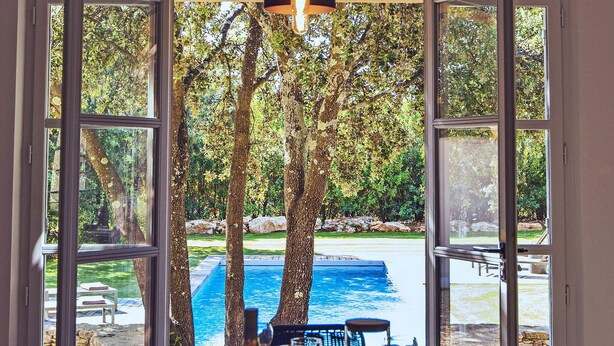 A view from a window with a pool and trees, a stone wall, and outdoor furniture. - Awesome home in Saint Siffret with WiFi (Saint Siffret)
