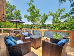Une terrasse dotée de meubles en osier, d’une table et d’un parasol.