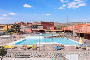 Un hotel con piscina, mobiliario exterior y vistas del paisaje circundante.
