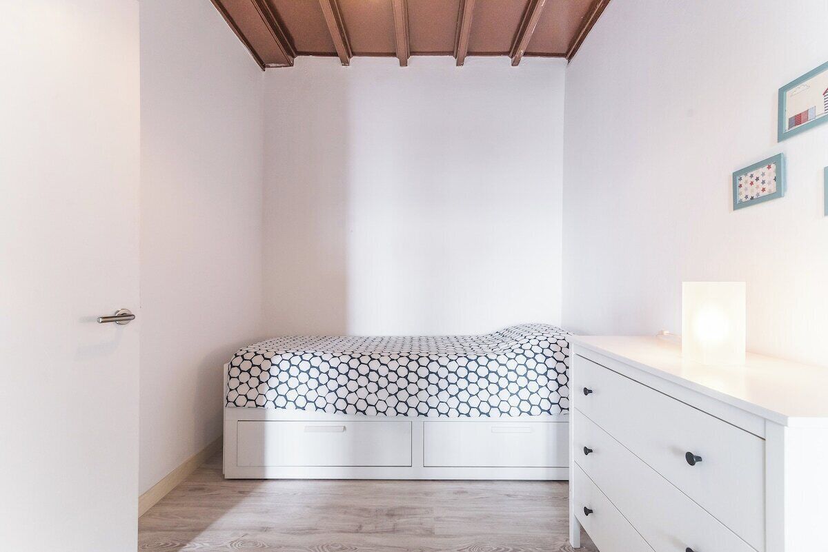 Ein Schlafzimmer mit einem Bett, einer Kommode und einer Tür.