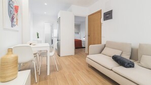 Un salon moderne avec un canapé, une table à manger et des chaises. Une porte donne accès à une autre pièce.