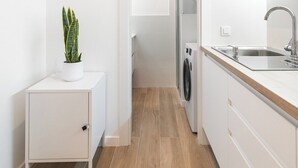 Une cuisine moderne avec des meubles blancs, un évier en acier inoxydable et une plante en pot.