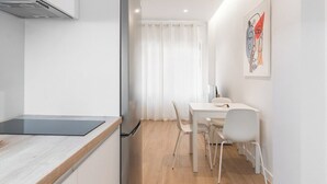 Une cuisine moderne équipée d’une cuisinière intégrée, d’un réfrigérateur et d’un coin repas avec une table et des chaises.