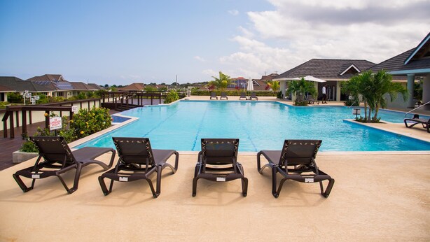 A swimming pool with lounge chairs and a view of surrounding houses. - Sunshine Paradise Villa (St. Ann's Bay)