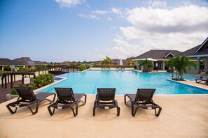A swimming pool with lounge chairs and a view of surrounding houses. - Sunshine Paradise Villa (St. Ann's Bay)