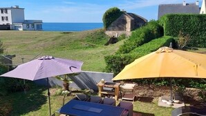 Eine Terrasse mit Gartenmöbeln, Sonnenschirmen und Meerblick.