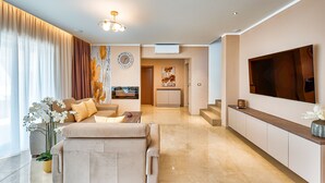 A modern living room with a sofa, coffee table, and potted orchids. There is a TV mounted on the wall and a staircase leading to another room. - Big pool with counter current swimming system, family and pat friendly.  (Labin)