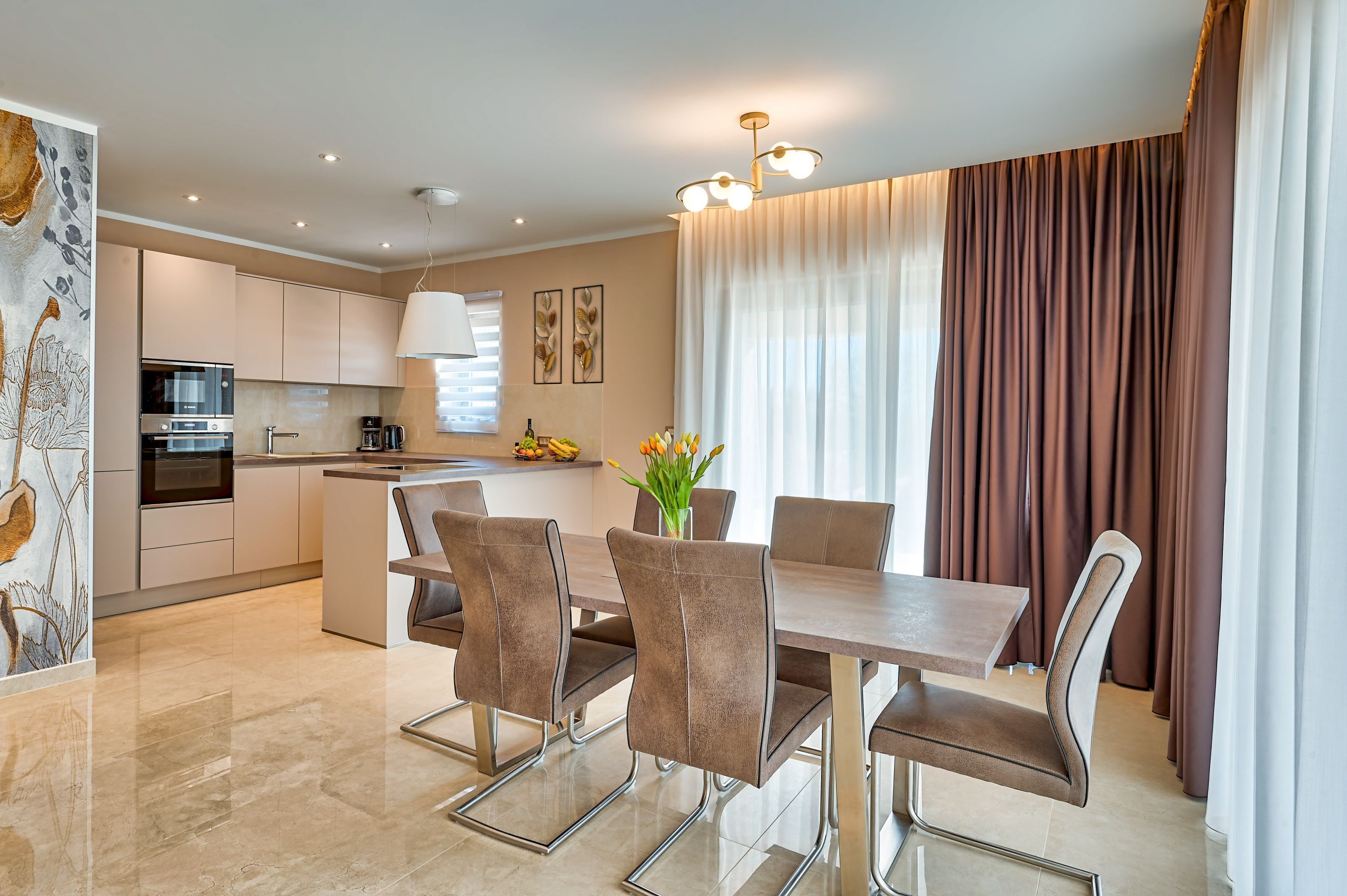 A modern kitchen with a central island, stainless steel appliances, and a dining area with a table and chairs.