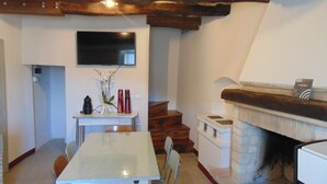 Un espace repas comprenant une table, des chaises, une cheminée et un téléviseur fixé au mur.