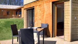 A wooden building with a patio area featuring a table and four chairs.