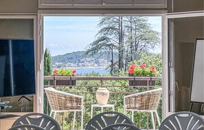 Enjoy the serene view of the coastal town from this balcony, featuring a comfortable seating area with a table and decorative accents.