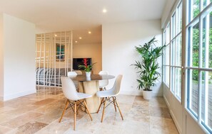 A modern dining area with a round table, white chairs, and a potted plant. - 10 bedroom amazing home in Le Pradet (Le Pradet)