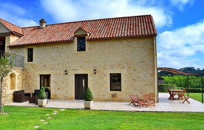 A stone building with a tiled roof, a balcony, and outdoor seating. - La Grange Des Endrevies (Sarlat La Caneda)
