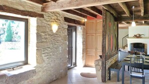 A rustic interior with exposed wooden beams, stone walls, a dining area with a table and chairs, and a fireplace. - La Grange Des Endrevies (Sarlat La Caneda)