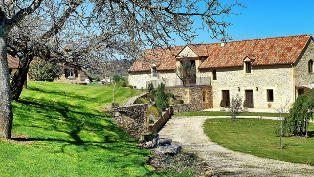 A stone building with a red-tiled roof, a stone pathway leading to the entrance, and a well-maintained lawn. - La Grange Des Endrevies (Sarlat La Caneda)