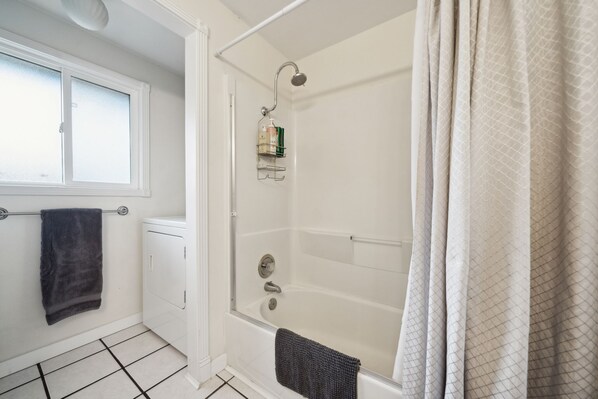 Un baño con bañera, ventana y perchero.