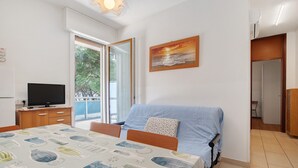 A bedroom with a bed, a television, a window, and a painting. - Apartment 'Condominio Lara A16' with Private Terrace and Air Conditioning (Jesolo)