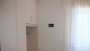 A room with a wardrobe, a small shelf, and a sign on the wall. - Apartment 'Residence Rubino Benelux 01' with Shared Pool, Terrace, and Air Conditioning (Jesolo)