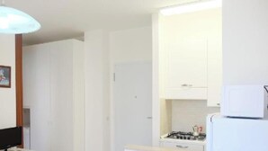 A kitchen with a gas stove, a microwave, and a refrigerator. - Apartment 'Residence Rubino Benelux 01' with Shared Pool, Terrace, and Air Conditioning (Jesolo)