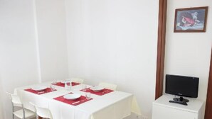 A dining area with a table set for four, a television on a stand, and a framed picture on the wall. - Apartment 'Residence Rubino Benelux 01' with Shared Pool, Terrace, and Air Conditioning (Jesolo)