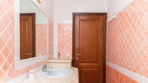 Une salle de bain avec un lavabo, un miroir et une porte en bois.