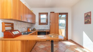 Une cuisine avec des meubles de rangement en bois, un évier, une cuisinière et une fenêtre.