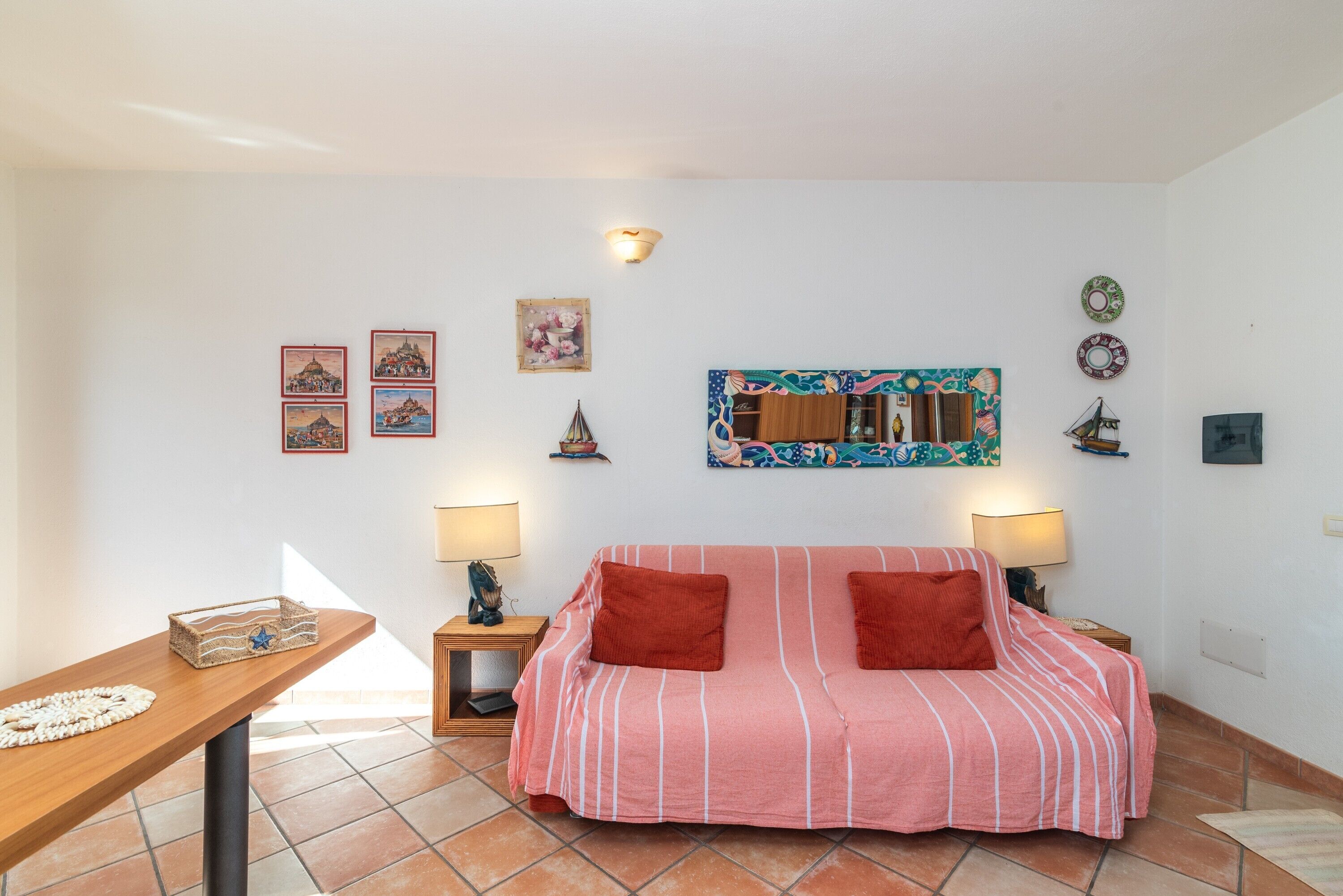A room with a striped sofa, two side tables with lamps, a wooden side table with a decorative item, and wall-mounted artwork.