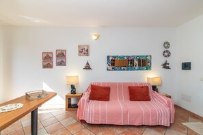 Une pièce comprenant un canapé à rayures, deux tables d’appoint avec des lampes, une table d’appoint en bois ornée d’un objet décoratif et des œuvres d’art accrochées au mur.