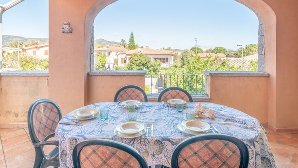 Un coin repas avec une table dressée pour quatre personnes, une vue sur le quartier environnant et un élément décoratif mural.