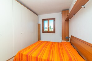 Une chambre à coucher avec un lit, une armoire, une fenêtre donnant sur un beau paysage et une étagère.
