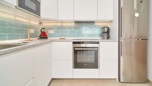 A modern kitchen with white cabinets, a stainless steel oven, a refrigerator, and a tiled backsplash. - Apartment 'Apartamento Moderno' with Sea View, Wi-Fi and Air Conditioning (Almuñecar)