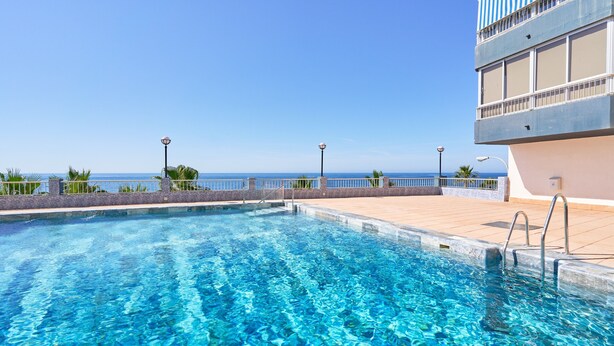 A clear blue pool with a view of the ocean, a balcony with a railing, and a building with large windows. - Apartment 'Apartamento Moderno' with Sea View, Wi-Fi and Air Conditioning (Almuñecar)