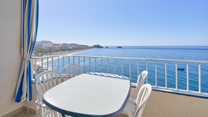 A balcony with a table and chairs, overlooking a coastal view with buildings and the sea. - Apartment 'Apartamento Moderno' with Sea View, Wi-Fi and Air Conditioning (Almuñecar)
