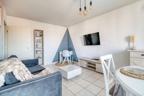 Un salon moderne comprenant un canapé, une table basse, un téléviseur et un bureau avec une chaise.