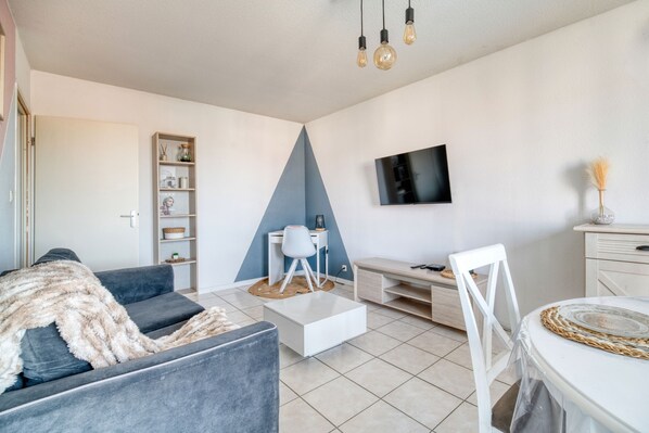 Un salon moderne comprenant un canapé, une table basse, un téléviseur et un bureau avec une chaise.