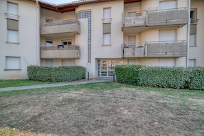 A multi-story residential building with balconies, a central staircase, and a small entrance.