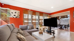 A living room with a sofa, a coffee table, a flat-screen TV, and a dining area with a table and chairs. - Holiday Home 'Goleta' with Private Pool, Wi-Fi and Air Conditioning (El Puerto de Santa María)