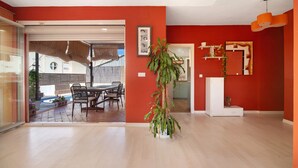 An interior with a dining area, a large potted plant, and a red accent wall. - Holiday Home 'Goleta' with Private Pool, Wi-Fi and Air Conditioning (El Puerto de Santa María)