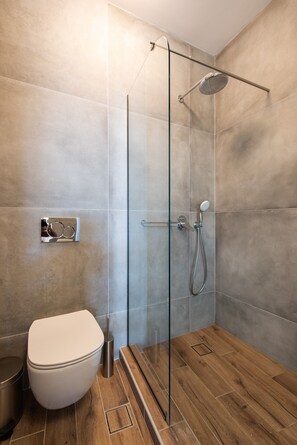 Een moderne badkamer met een glazen douchecabine, een toilet en een bidet.