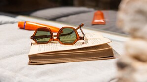 Une paire de lunettes posée sur un livre, avec un stylo et une bouteille sur une surface.