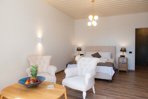 Een slaapkamer met een bed, twee nachtkastjes, een stoel, een klein tafeltje met een schaal fruit en een hanglamp.