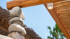 Un empilement de pierres sous une structure en bois, avec un luminaire placé au-dessus.