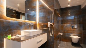 A modern bathroom with a glass shower enclosure, a white sink, and a toilet. - White & Black Suites – Suite Three (Platys Gialos)