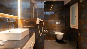 Een moderne badkamer met een witte wastafel, een douchecabine van glas en een toilet.