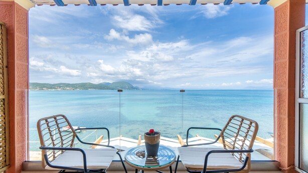 A balcony with two chairs and a table, overlooking a body of water and distant land. - Studio Apartment 'Nikos Seaside  4' with Sea View, Wi-Fi and Air Conditioning (??????a)