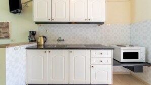 A kitchen with white cabinets, a microwave, a coffee maker, and a tiled backsplash. - Studio Apartment 'Nikos Seaside  4' with Sea View, Wi-Fi and Air Conditioning (??????a)