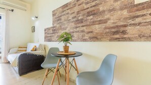 A modern living room with a bed, a table with a plant, and two chairs. - Studio Apartment 'Nikos Seaside  4' with Sea View, Wi-Fi and Air Conditioning (??????a)
