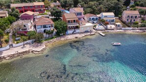 A coastal residential area with houses, a clear blue sea, and a small boat. - Studio Apartment 'Nikos Seaside  5' with Sea View, Wi-Fi and Air Conditioning (??????a)