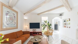 Una sala de estar con un sofá, dos mesas auxiliares, un televisor y una planta.